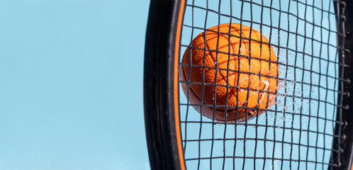 A hit with a tennis racket to a wet ball, on a background of blue sky, close up view