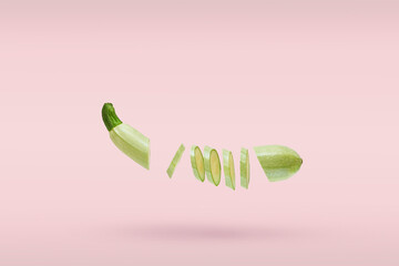 One vegetable marrow fresh sliced many small slices flying on pink background. Concept levitation food. Copy space for text.