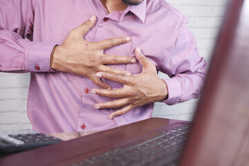 young man suffering pain in heart and holding chest with hand 