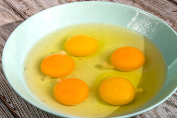 Broken chicken eggs in a bowl of pale turquoise color, 5 pieces. Topic: cooking recipes, baking, whipping sponge cake, cooking scrambled eggs, healthy natural products. Background. 