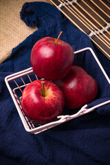 Three bright red apples on a blue cloth