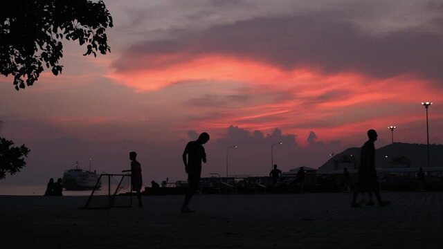 Children play soccer on the pier after sunset. 