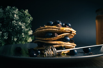 Tower of pancakes with honey, blueberries and dark chocolate
