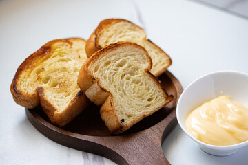 Toast in wooden plate with cheese on gray background