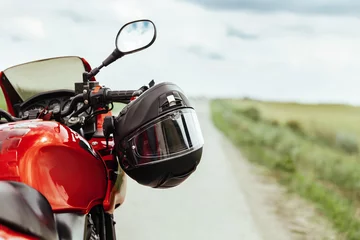 Foto auf Acrylglas Motorrad Schwarzer Motorradhelm, der am Lenker des Motorrads hängt