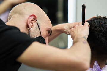 Obraz na płótnie Canvas hairdresser cutting hair of client with mask