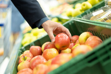 A young man touches apples to determine his quality in the supermarket