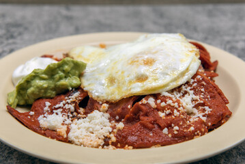 Chilaquiles smothered in red sauce and topped with scrambled egg makes for a hearty and filling breakfast.