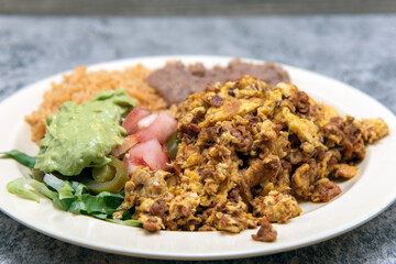 Hearty plate of Mexican food of Chorizo and eggs served with refried beans and rice.