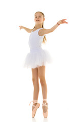 Fototapeta na wymiar Cute little girl in a tutu and pointe shoes dancing in the studio on a white background.