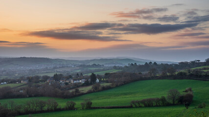 Fototapeta na wymiar Beautiful vibrant sunrise landscape image of misty view towards Symondsbury village in Dorset on a Spring morning