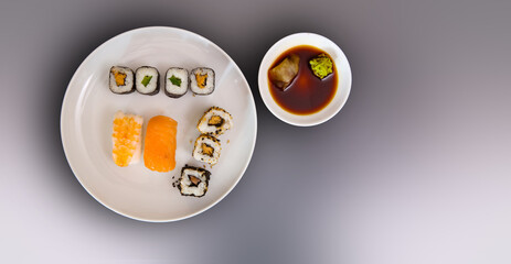 Set of sushi on grey background on white plates