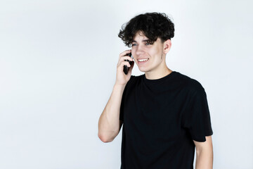 The teenage boy talks on the phone and smiles, he has not talked to a friend for a long time, and the guy is always in a good mood after talking to a friend