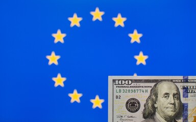 100 US dollars banknote close up on blurred background of European Union flag