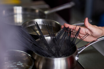 nera pasta is manually dipped in a pot of boiling water in the kitchen