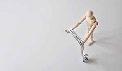 Wooden mannequin. Measuring meter - symbolizes sewing clothes or weight control. Gray background.