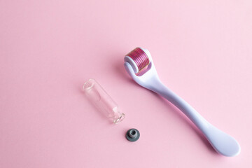 derma roller, meso scooter, gold micro needles and hyaluronic acid ampoule on a pink background....