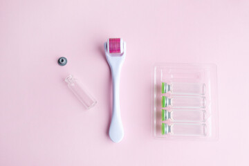 derma roller, meso scooter, gold micro needles and hyaluronic acid ampoules on a pink background....