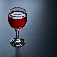 Glass of red wine on a dark background.