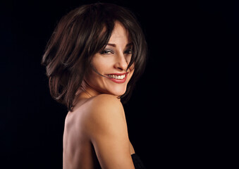 Fototapeta premium Happy laughing bright makeup woman shaking her black short hair on black background. Closeup portrait