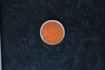 Red lentils close-up. Background with lots of lentils. Minimalism. Black background. Top view. Soft focus