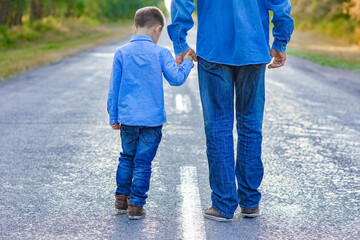 A Happy parent with a child in the park hands on nature travel go along the road