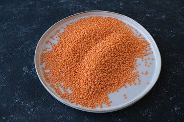 Red lentils close-up. Background with lots of lentils. Minimalism. Black background. Top view. Soft focus