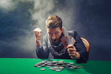 Happy poker player winning and holding a pair of aces