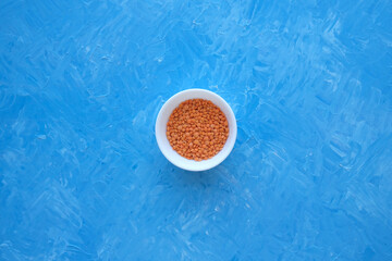 Red lentils close-up. Background with lots of lentils. Minimalism. Blue background. Top view. Soft focus