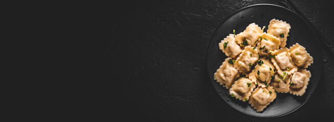 Meat dumplings - russian pelmeni, ravioli with meat in black plate on Dark grey black slate background