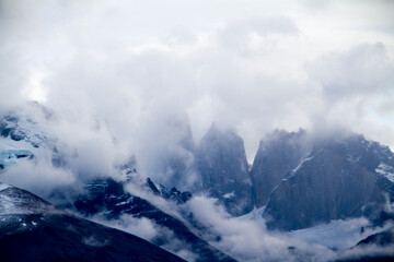 High snow moutain peaks among clouds, Torres del Paine.