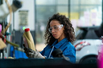 A female car mechanic holding a bottle of brake fluid and engine oil to be exchanged for a customer. Auto mechanic female automotive diagnostic Checking car service, repair, maintenance.