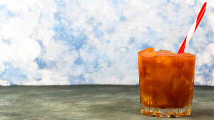 Glass of tomato juice with ice. Red and white straw in cocktail. Drink for party, vegetarian diet. Copy space for text