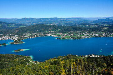 Blick aus gr0ßerer Höhe auf einen wunderschönen See, umrandet von Bergen, an einem wolkenlosen Sommertag.