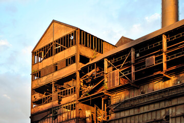 Old dilapidated rusty factory hall in bright sunlight
