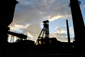 Old mining tower silhouette, framed by factory hall and chimney