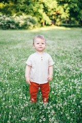 Portrait of a happy little caucasian toddler boy in the park. Kids fashion clothing, spend time outdoors at nature. Funny baby smile to camera
