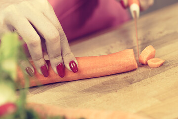 Woman cutting carrot on kitchen board