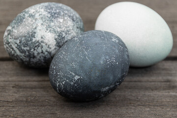 Three painted blue easter eggs on wooden table.