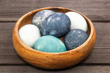 Wooden plate with easter eggs on table, marble blue color. Decorating holiday with traditional dishes. Breakfast at farm