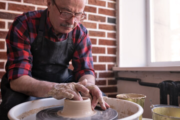 Senior male potter creating bowl in pottery workshop.