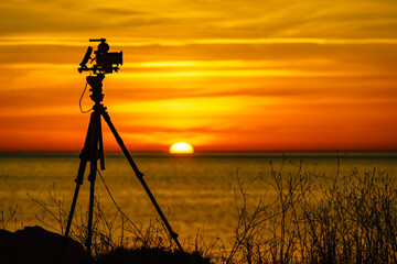 Camera taking picture of sunrise over sea