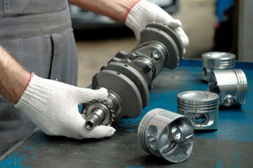 New crankshaft close-up. A set of engine pistons on the car mechanic's desktop. Quality control of...