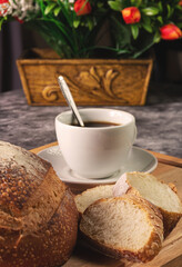 Italian bread and coffee, with flowers on a blurred background. Wooden base.