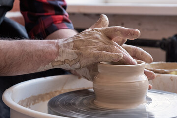 Potter wheel and hands of craftsman making a jug