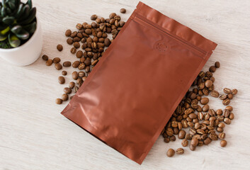 Blank coffee packaging on a wooden table, with coffee seeds, with decorative flower on a wooden background, coffee packaging mockup with empty space to display your branding design. Top view.