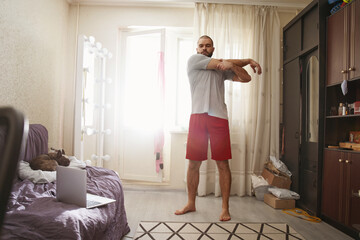 Man stretching his arms while doing morning exercise at home