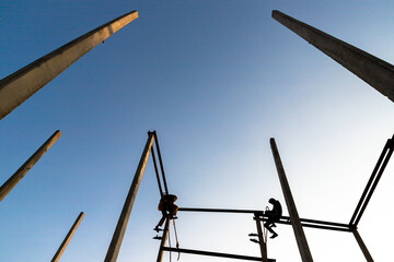 silhouette of a man sitting on electric pole.