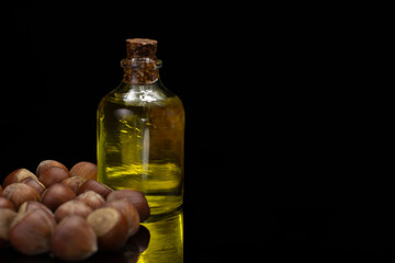 Bottle of hazelnut kernels and hazelnut oil on a black mirror