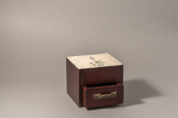 Brown wooden box with open drawer with gold decoration handle on jewellery.